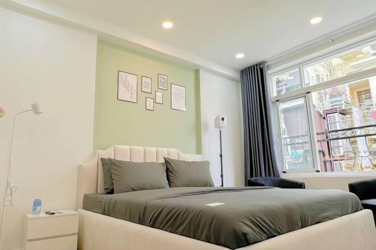 Ein Schlafzimmer mit Bett, Nachttisch, Wandbild und einem Fenster mit Blick.