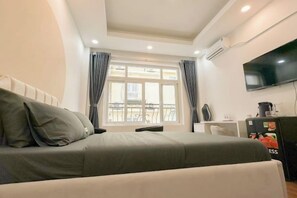 A hotel room with a bed, a TV, a desk, and a balcony view.