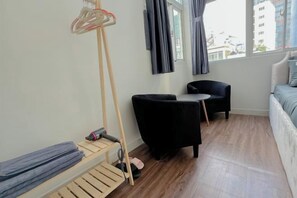 A room with a bed, a chair, a small table, a window with curtains, and a wooden floor. - Aesthetic homes Bui Vien Street (Ho Chi Minh City)