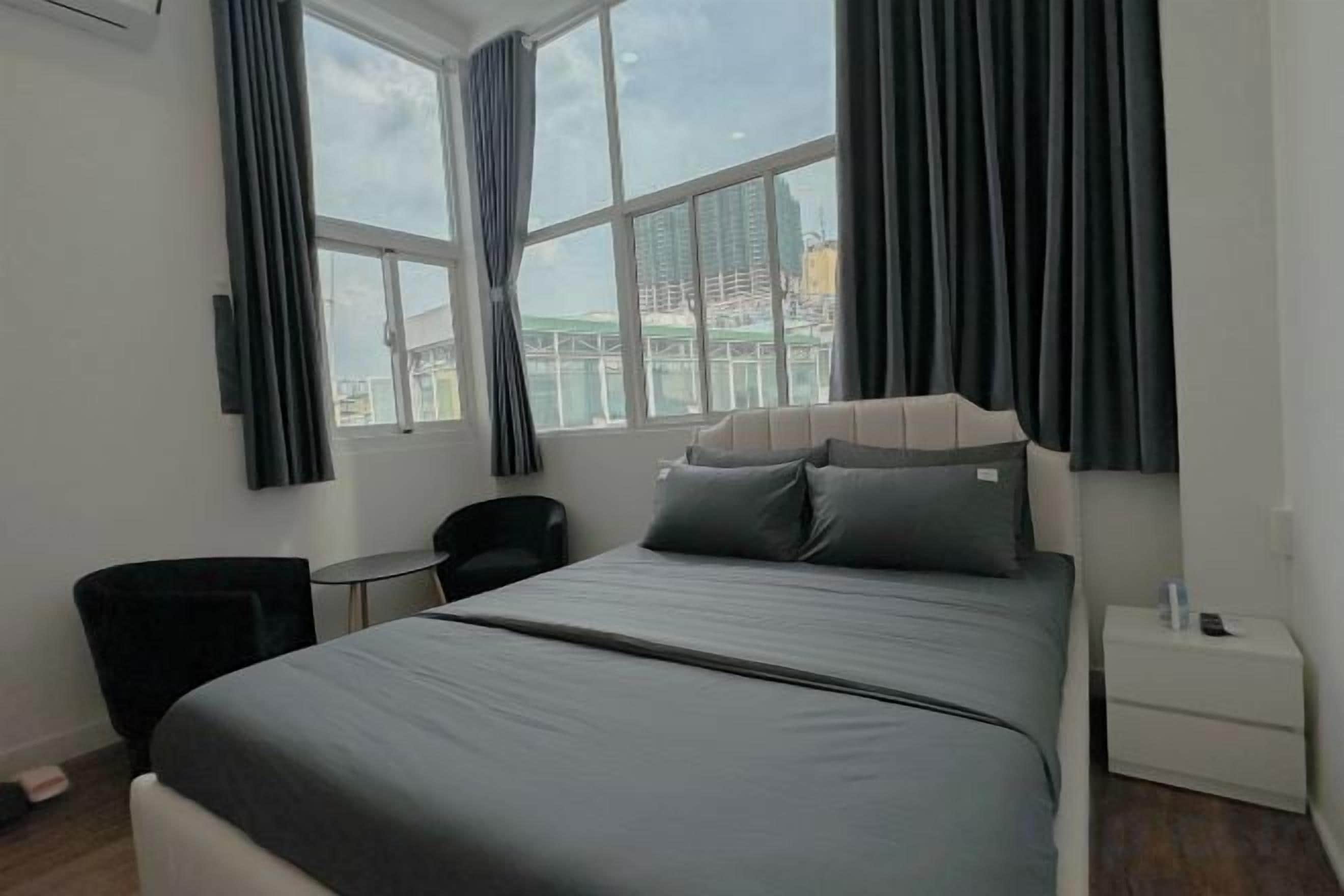A modern hotel room with a large bed, a desk, and a chair.