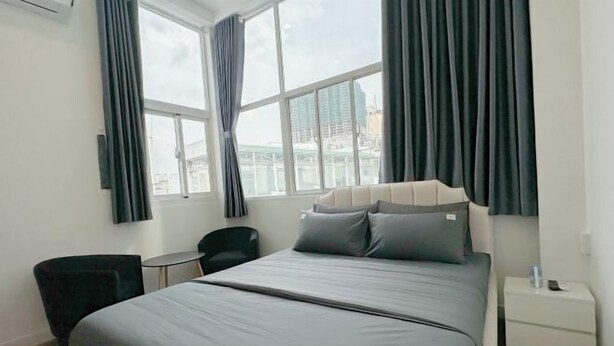 A modern hotel room with a large bed, a small desk, a chair, and a window with curtains. - Aesthetic homes Bui Vien Street (Ho Chi Minh City)