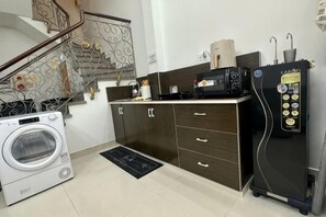 A compact kitchen with a washing machine, a microwave, and a refrigerator. - Aesthetic homes Bui Vien Street (Ho Chi Minh City)