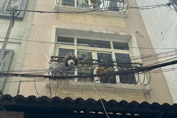 Un immeuble doté d’un balcon, d’une fenêtre agrémentée de fleurs et de nombreuses lignes électriques.