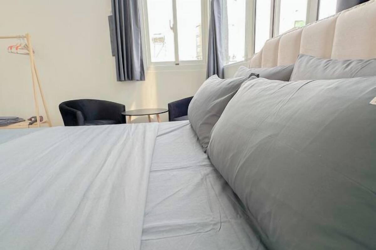 Ein Hotelzimmer mit einem großen Bett, einem kleinen Tisch, einem Stuhl und einem Fenster mit Vorhängen.