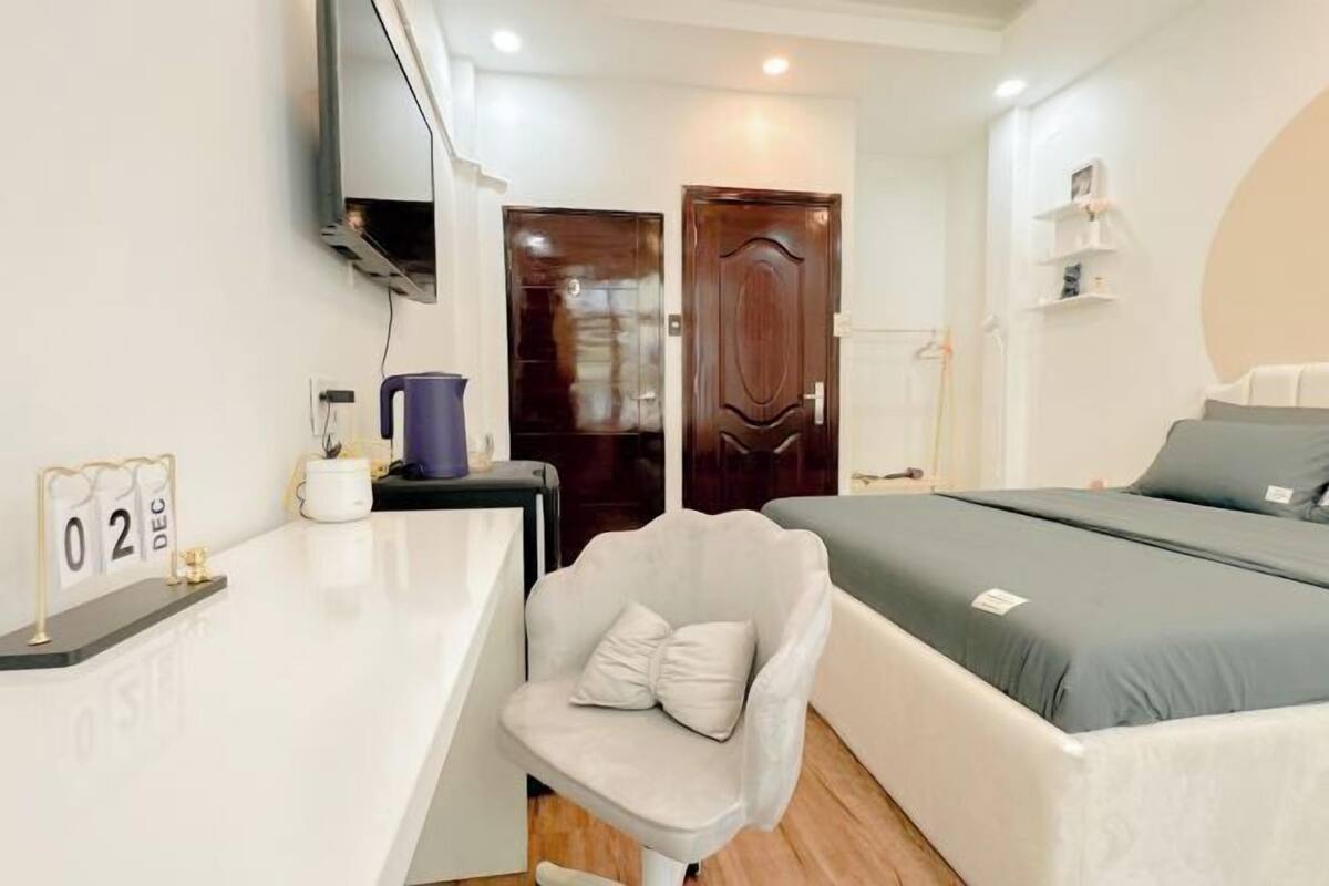 Una habitación de hotel moderna con una cama, un escritorio con un calendario, una silla y un televisor montado en la pared.