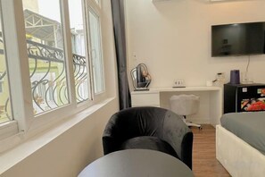 A room with a bed, a desk, a chair, a TV, and a window with a view of a balcony. - Aesthetic homes Bui Vien Street (Ho Chi Minh City)