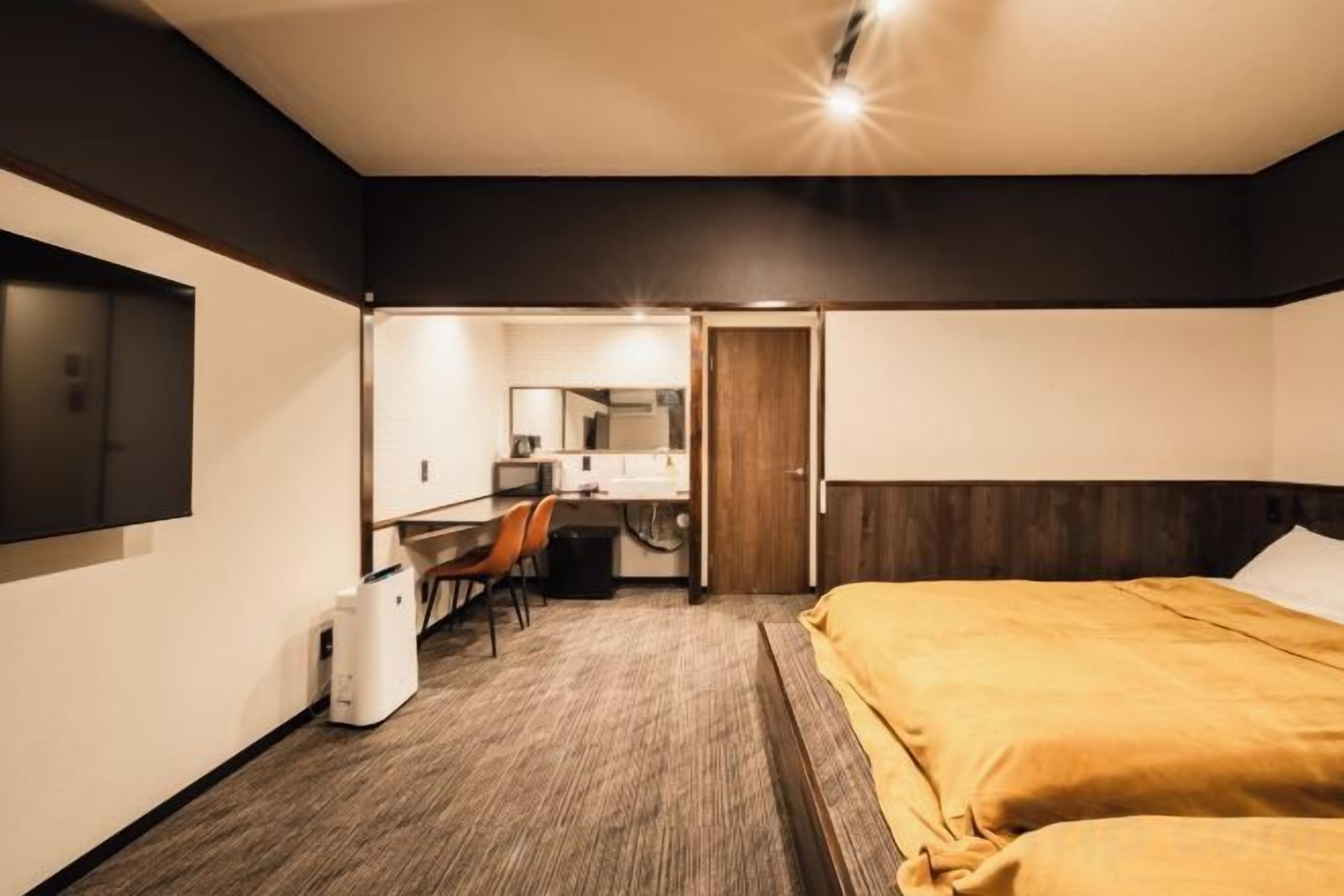 A hotel room with a bed, a desk, a chair, and a television.