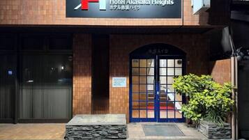 A hotel entrance with a prominent sign, a blue door, and a small step leading up to the entrance.