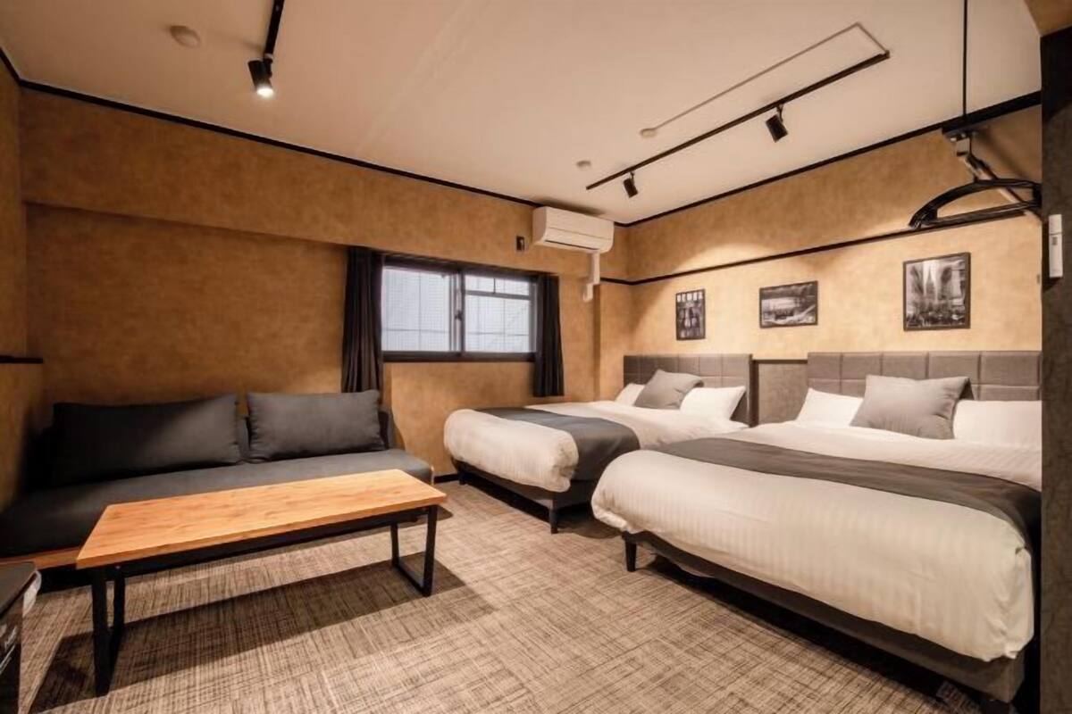Une chambre d’hôtel avec deux lits, un canapé, une table en bois et une fenêtre.