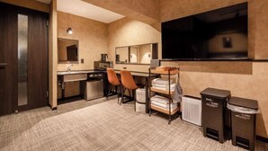 A hotel room with a large flat-screen TV, a desk with chairs, a mirror, a wardrobe, and a trash bin. - Hotel Akasaka Heights (Fukuoka)