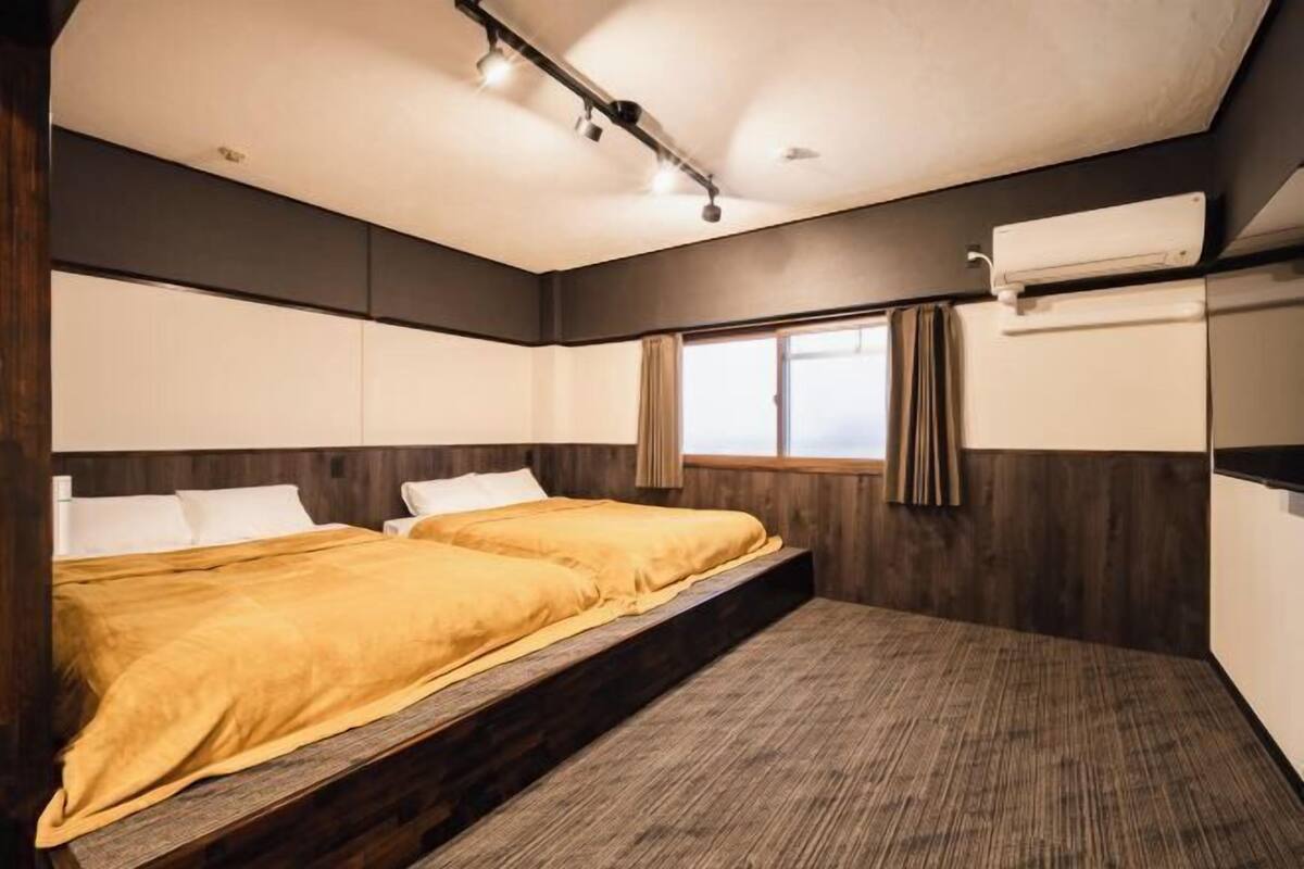 A bedroom with a bed, a window, and an air conditioning unit.