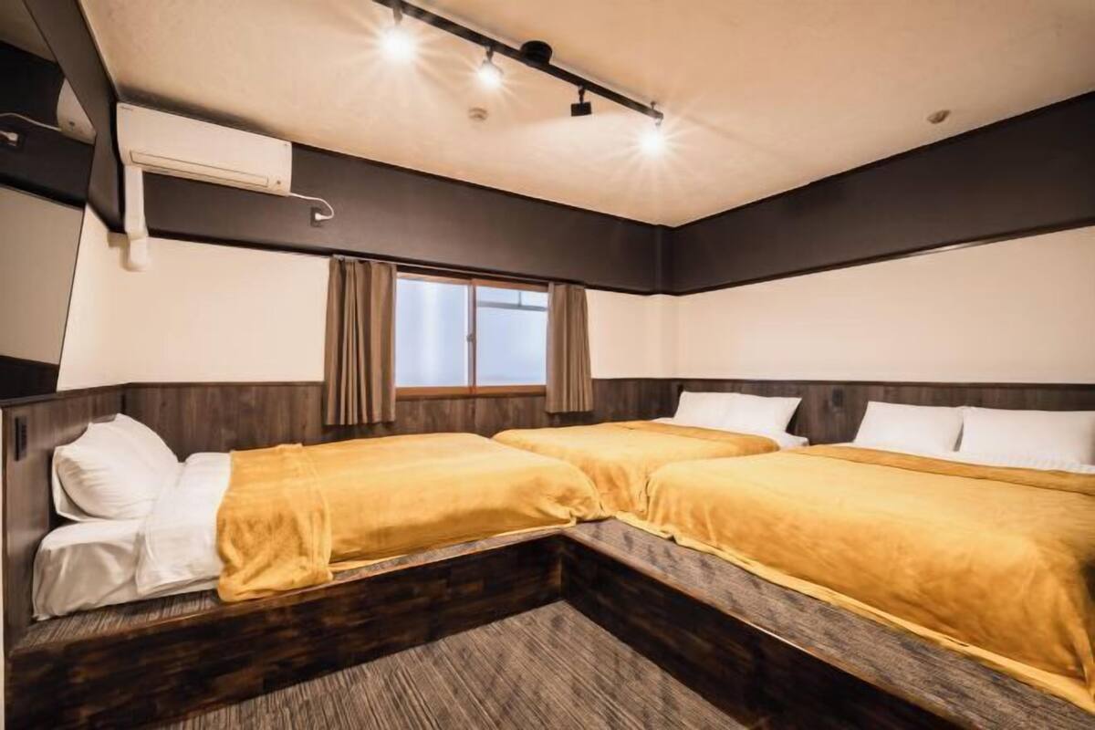 A hotel room with two beds, a window, and a ceiling light fixture.
