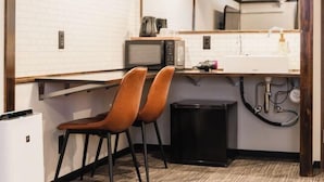 A compact kitchen with a microwave, sink, and two chairs. - Hotel Akasaka Heights (Fukuoka)