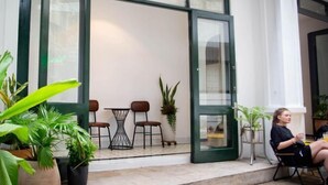An open door leading to a seating area with chairs and a table, surrounded by potted plants. - Violet Star Hotel (Ho Chi Minh City)