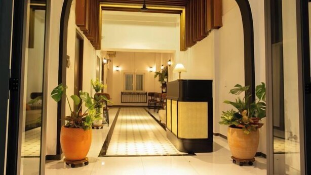 A hotel lobby with a central reception desk, a patterned floor, and potted plants. - Violet Star Hotel (Ho Chi Minh City)