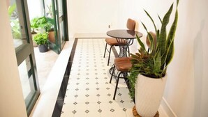 A hallway with a patterned floor, a small round table with chairs, and potted plants. - Violet Star Hotel (Ho Chi Minh City)