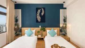 Camera d'albergo con due letti, vista sulla città, parete decorata in blu e un elemento decorativo a parete.