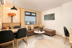 Una sala de estar moderna con una mesa de comedor, sillas, un sofá, una mesa redonda de centro y un ventanal grande.