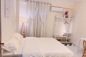 A bedroom with a bed, a bedside table, a chair, a wardrobe, and a desk. - Lemon Tree & Home 2 (New Cairo City)