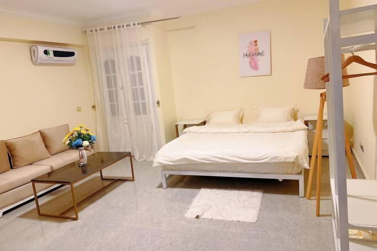 Una camera da letto con un letto, un divano, un tavolo e una poltrona sospesa.