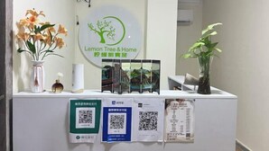 A reception desk with a sign reading "Lemon Tree & Home" and QR codes for services. - Lemon Tree & Home 2 (New Cairo City)