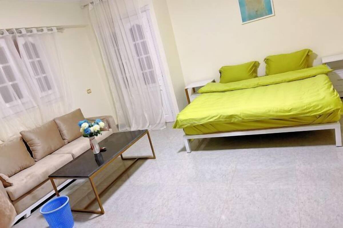 Una stanza con un letto, un divano, un tavolino e una finestra con tende.