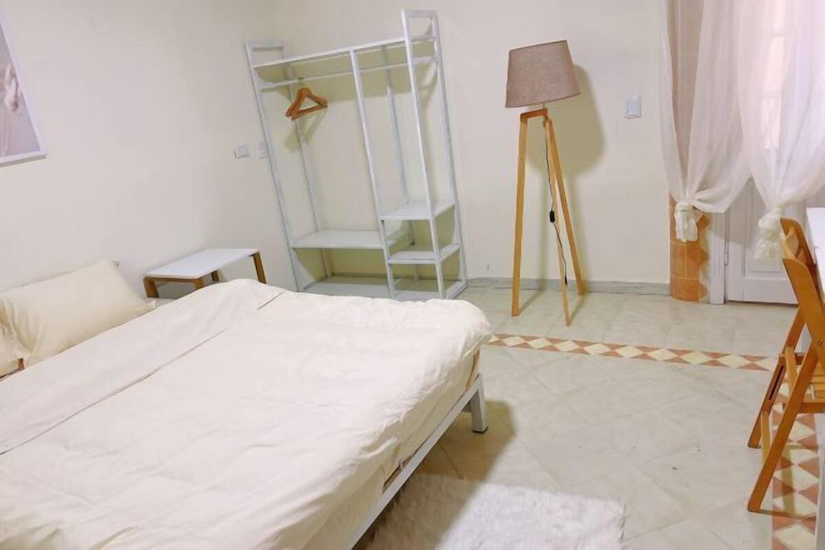 Una camera da letto con un letto, un armadio, una scrivania, una lampada e una sedia.