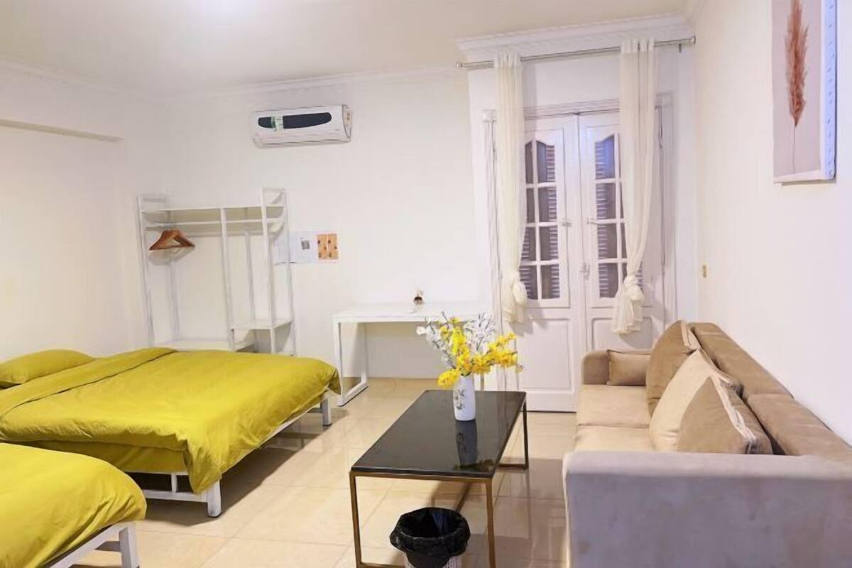 Una stanza con due letti, un divano, un tavolino e una finestra con tende.
