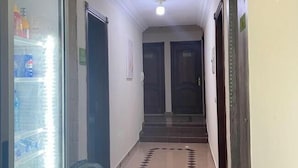 A narrow hallway with a tiled floor leading to a set of double doors. - Lemon Tree & Home 2 (New Cairo City)