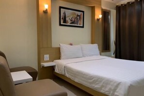 Camera d'hotel con un letto, un comodino, una sedia e una mensola a parete.