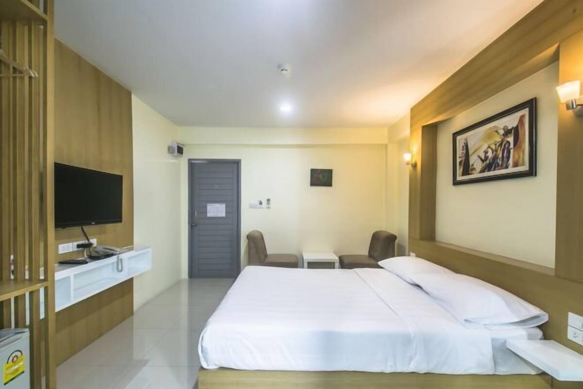 A hotel room with a bed, a TV, a desk, and a chair.