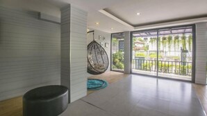 A spacious room with a large sliding glass door leading to a balcony with a view of greenery. - Petchsiri Boutique Hotel (Bangkok)