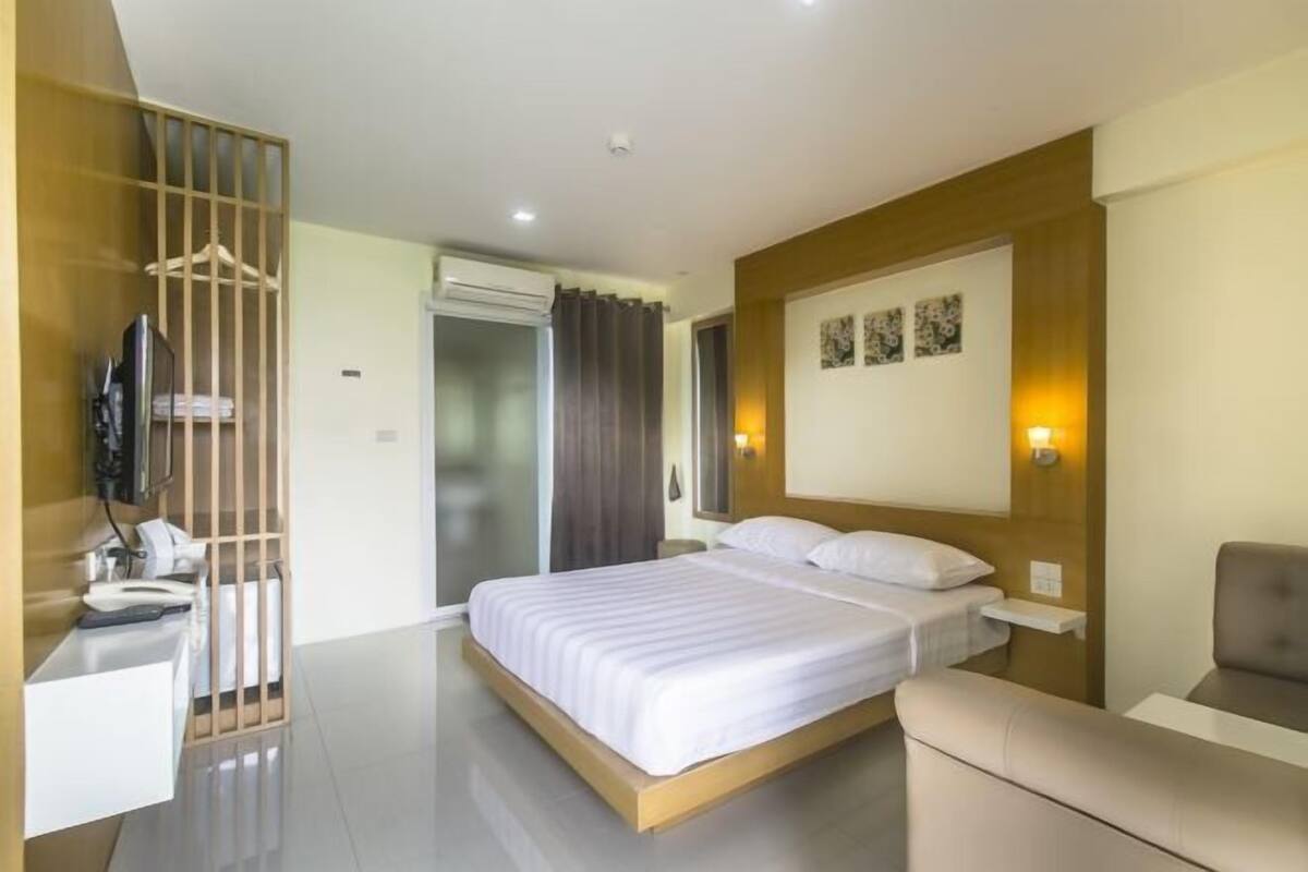 A modern hotel room with a large bed, a desk, a chair, and a TV.