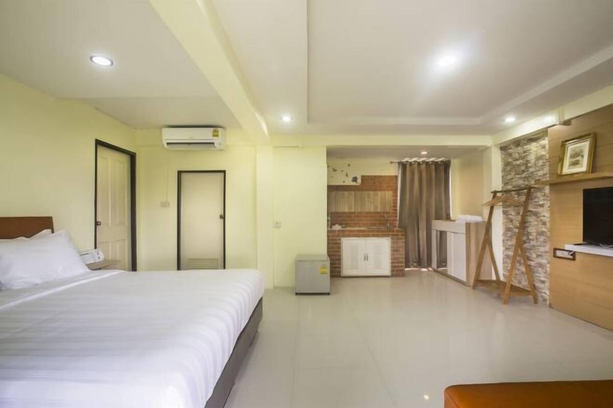 A hotel room with a bed, a desk, a television, and a kitchenette.