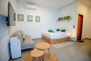 A modern bedroom with a bed, a sofa, a TV, and a small table. - Bali Bay By Urban Haven (Bali)