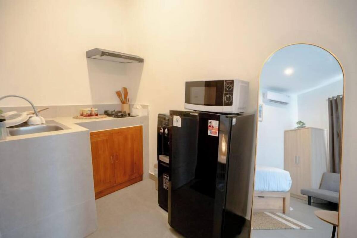 A compact kitchen with a microwave, refrigerator, and wooden cabinets.