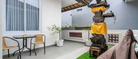 A patio with a dining area, a decorative stone structure, and a green artificial turf.