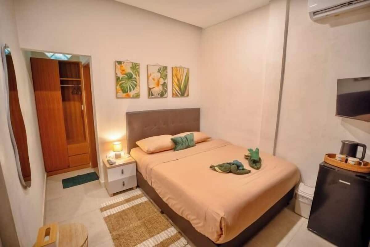 A bedroom with a bed, nightstand, and a small cabinet.