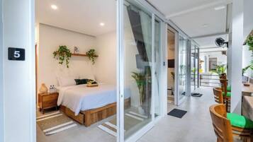Un dormitorio moderno con cama, mesita de noche y puerta corrediza de vidrio que da a un comedor.