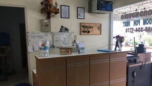 Een receptiebalie met een houten kast, een computer en verschillende papieren en berichten aan de muur.