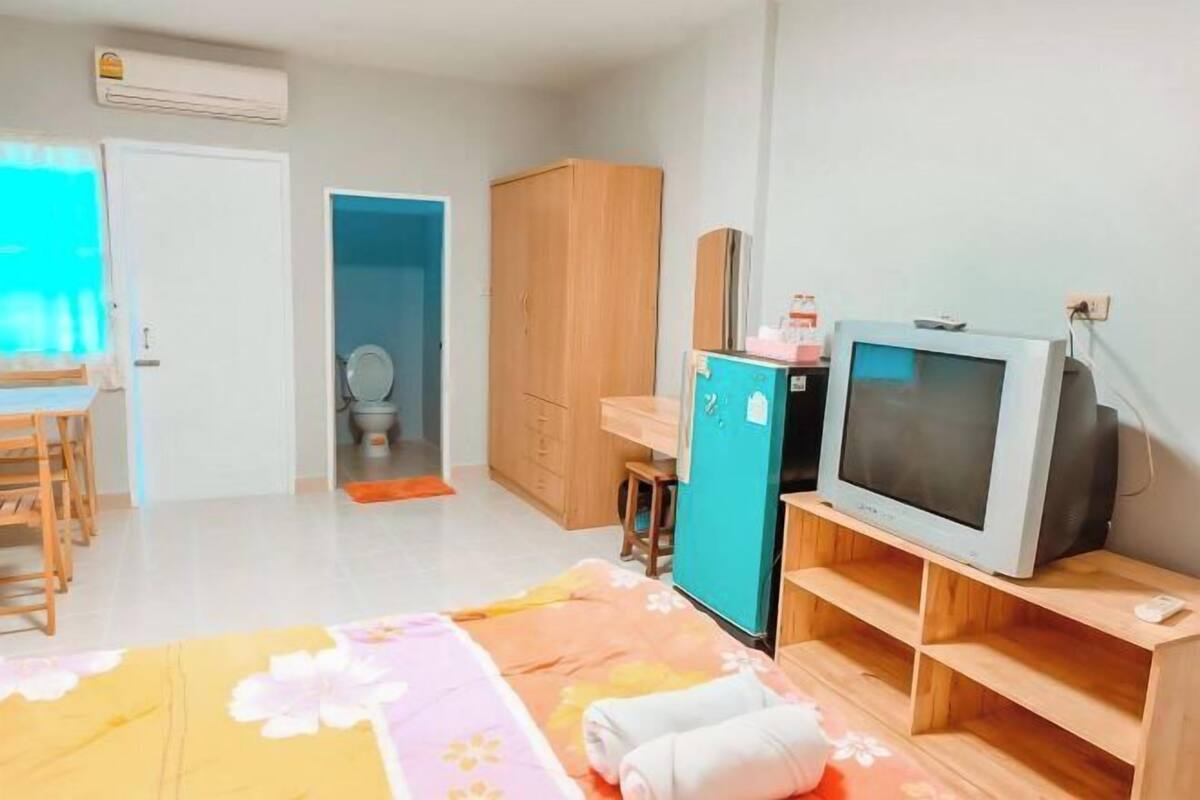 Une chambre à coucher comprenant un lit, un bureau, une télévision et une armoire.