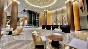 A modern lobby with a circular chandelier, seating areas, and a staircase in the background. - Wyndham Cam Ranh Villas (Cam Lam District)