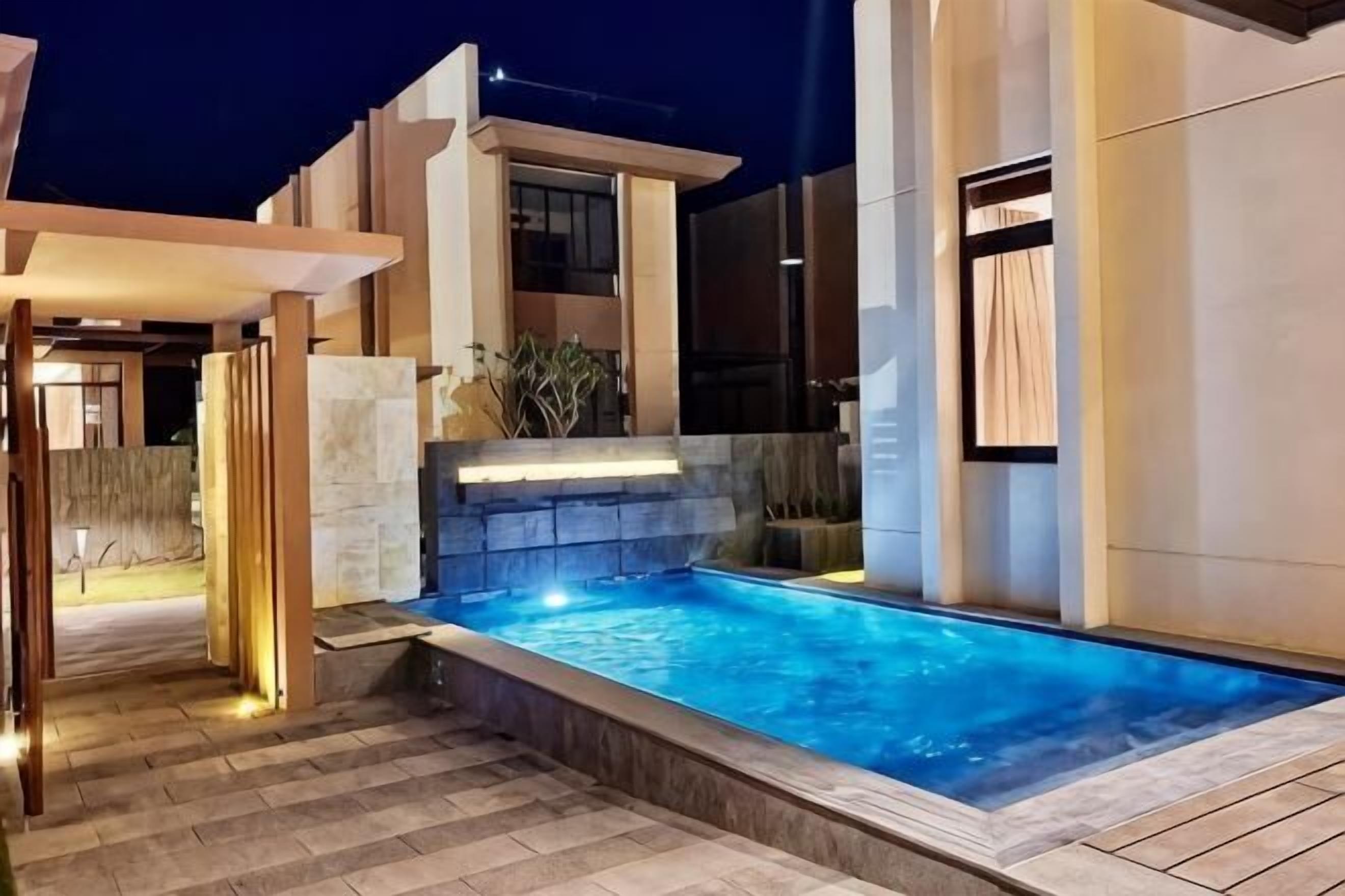 Ein moderner Außenpool mit Steinmauer und einer Pergola.