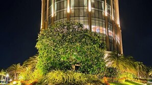 A tall building with a circular base, surrounded by well-maintained greenery and palm trees. - Wyndham Cam Ranh Villas (Cam Lam District)