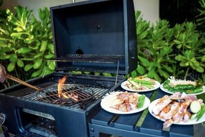 En grill med mat på tallrikar, omgiven av grönska.