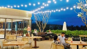 An outdoor seating area with tables and chairs, string lights overhead, and a view of the outdoors. - Wyndham Cam Ranh Villas (Cam Lam District)