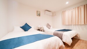 A hotel room with two beds, a nightstand, an air conditioning unit, and a window with curtains. - Waseda Star 101. New interior! For your stay in Tokyo, stay at the Waseda Star, 2 minutes from Waseda Station in Shinjuku-ku! (新宿区早稲田町)