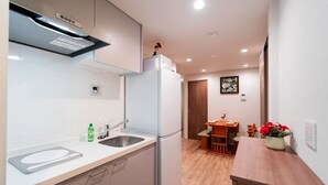 A compact kitchen with a refrigerator, sink, and wooden dining table. - Waseda Star 101. New interior! For your stay in Tokyo, stay at the Waseda Star, 2 minutes from Waseda Station in Shinjuku-ku! (新宿区早稲田町)