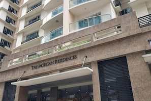 A multi-story building with balconies, a sign reading 'The Morgan Residences,' and large windows.