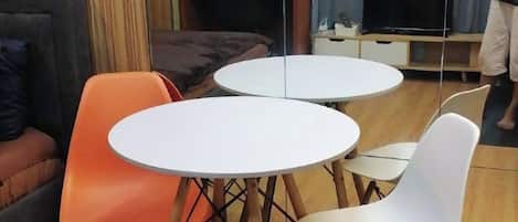 Una habitación con dos mesas redondas, una naranja y una blanca, y una silla blanca.